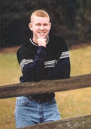 Jared Jamail smiling, leaning on a wooden fence